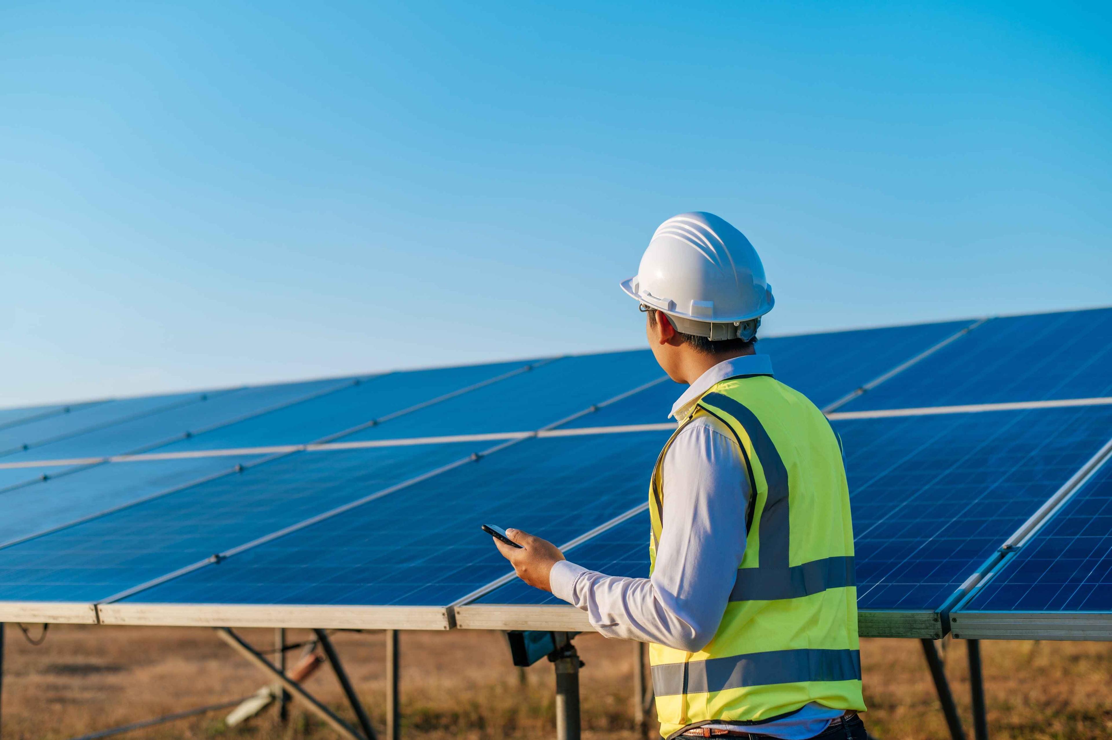 young technician standing in front of solar panels